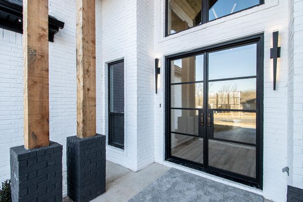 A white brick house with black sliding glass doors and windows.
