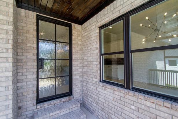A brick wall with a door and two windows on it.