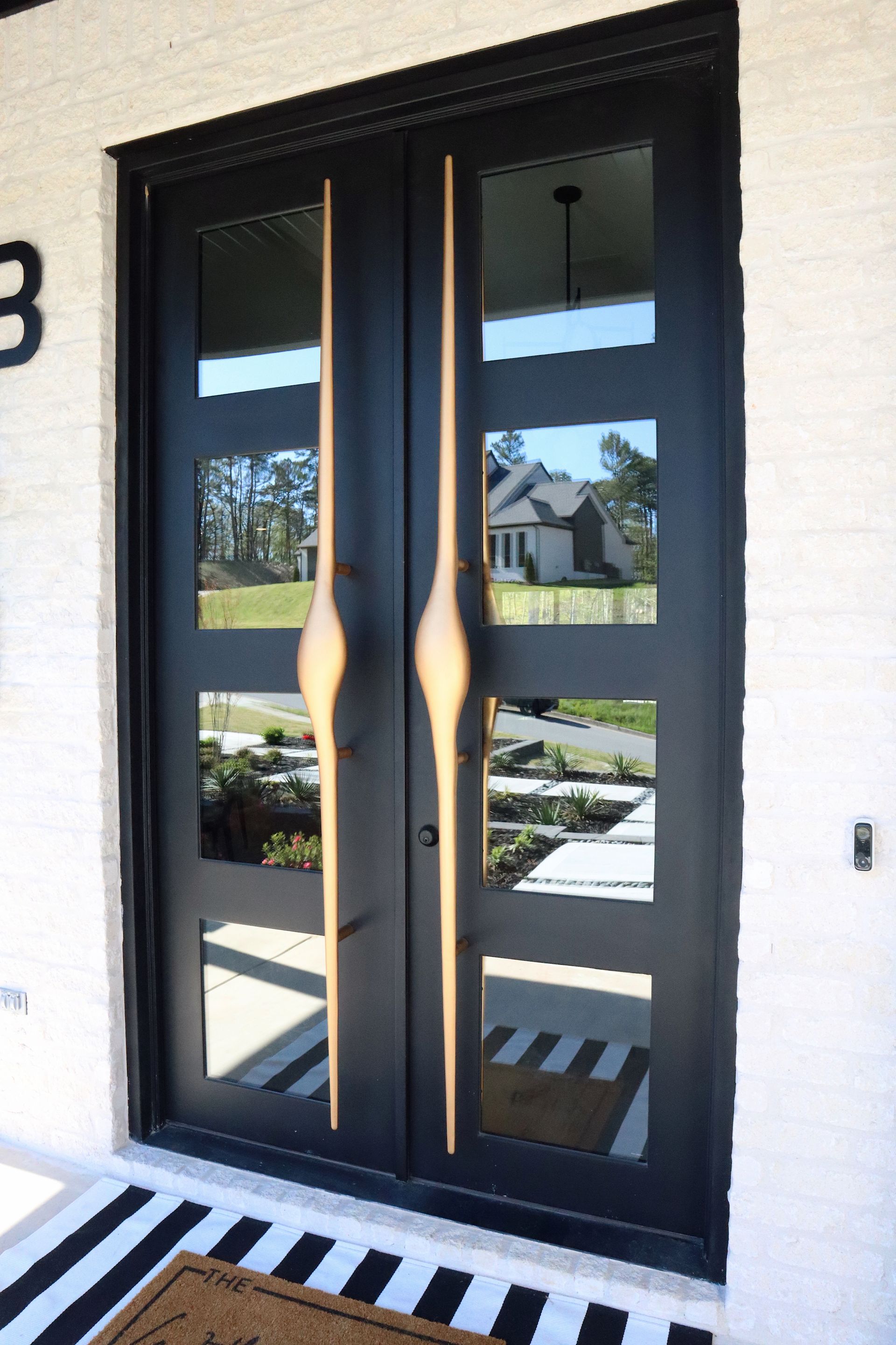 A black door with gold handles is on a white brick building.
