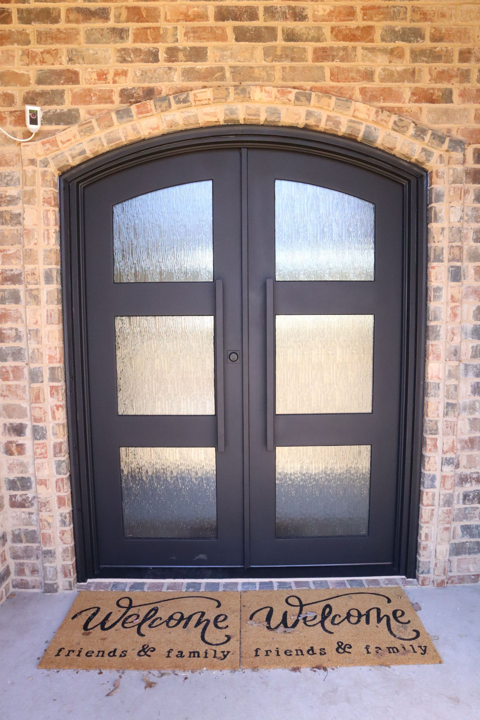 A black door with a welcome mat in front of it.