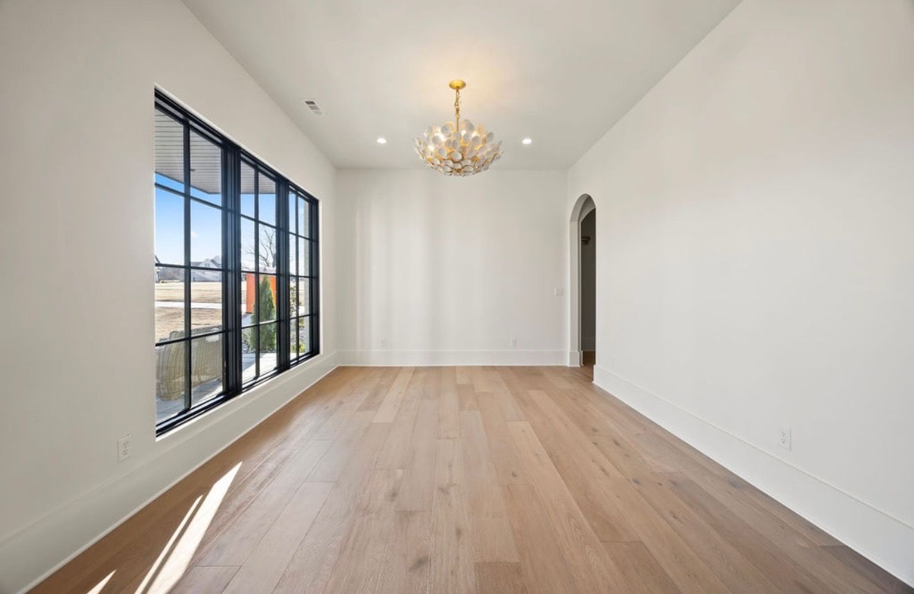 A large empty room with hardwood floors and a chandelier.