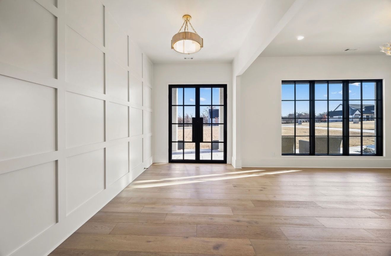 A large empty room with hardwood floors and white walls.