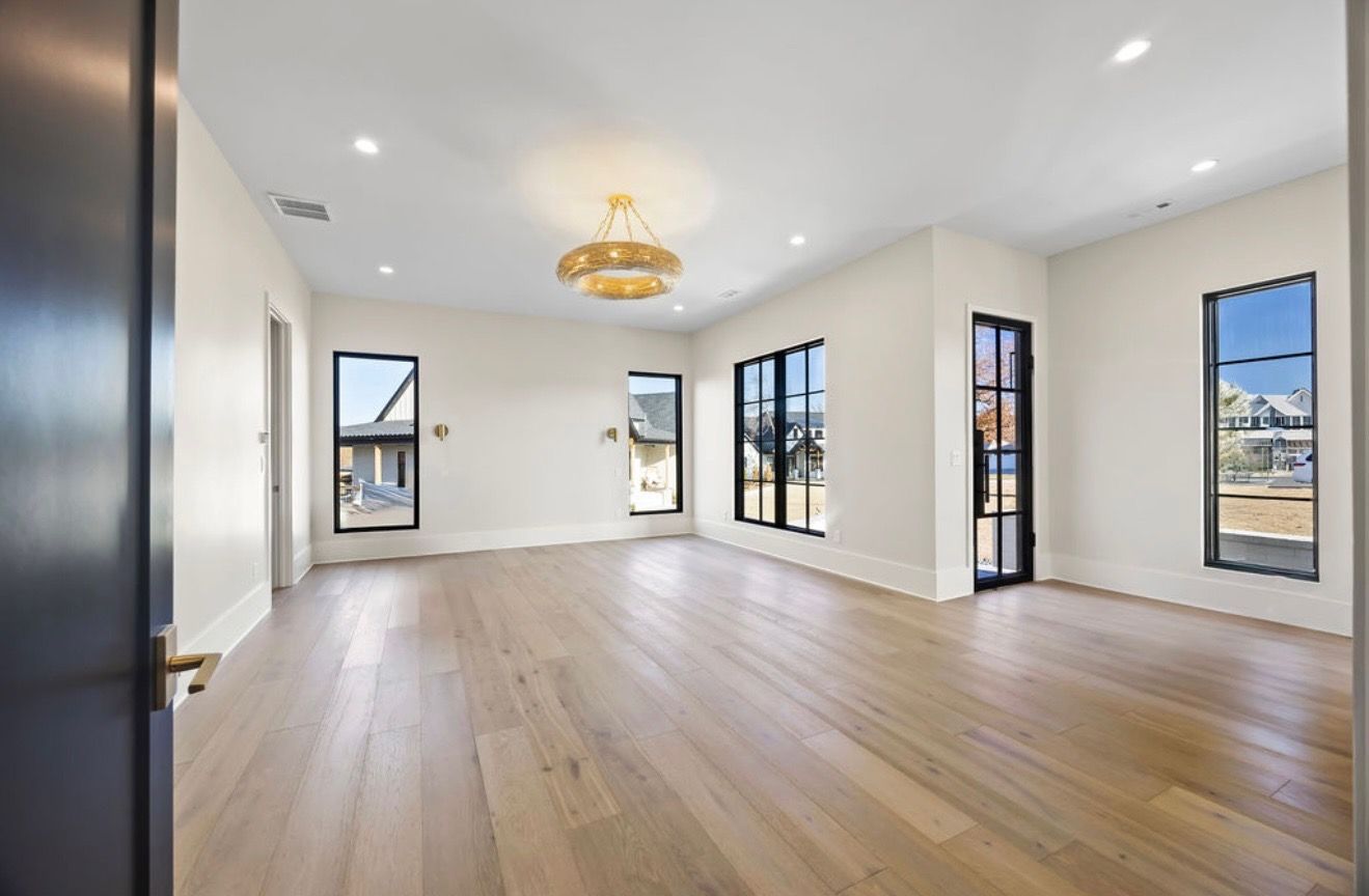An empty living room with hardwood floors and a chandelier.
