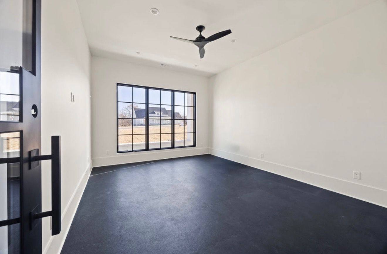 An empty room with a black floor and a ceiling fan.