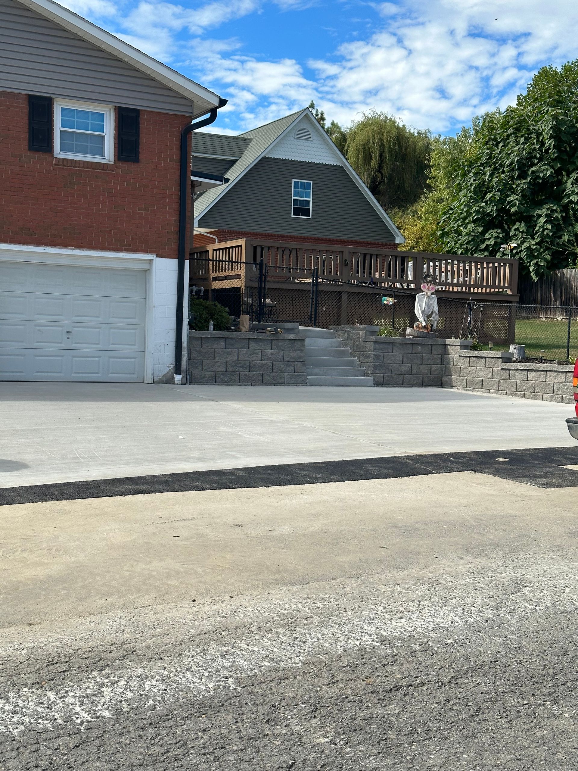 Brick house with a garage and a second story deck, built into a hillside.
