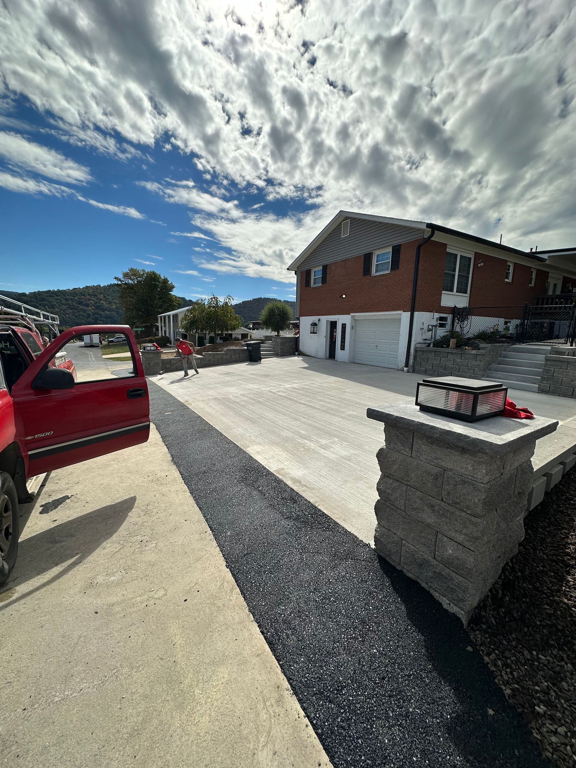 Red truck parked near a home with a newly paved driveway and stone retaining walls.