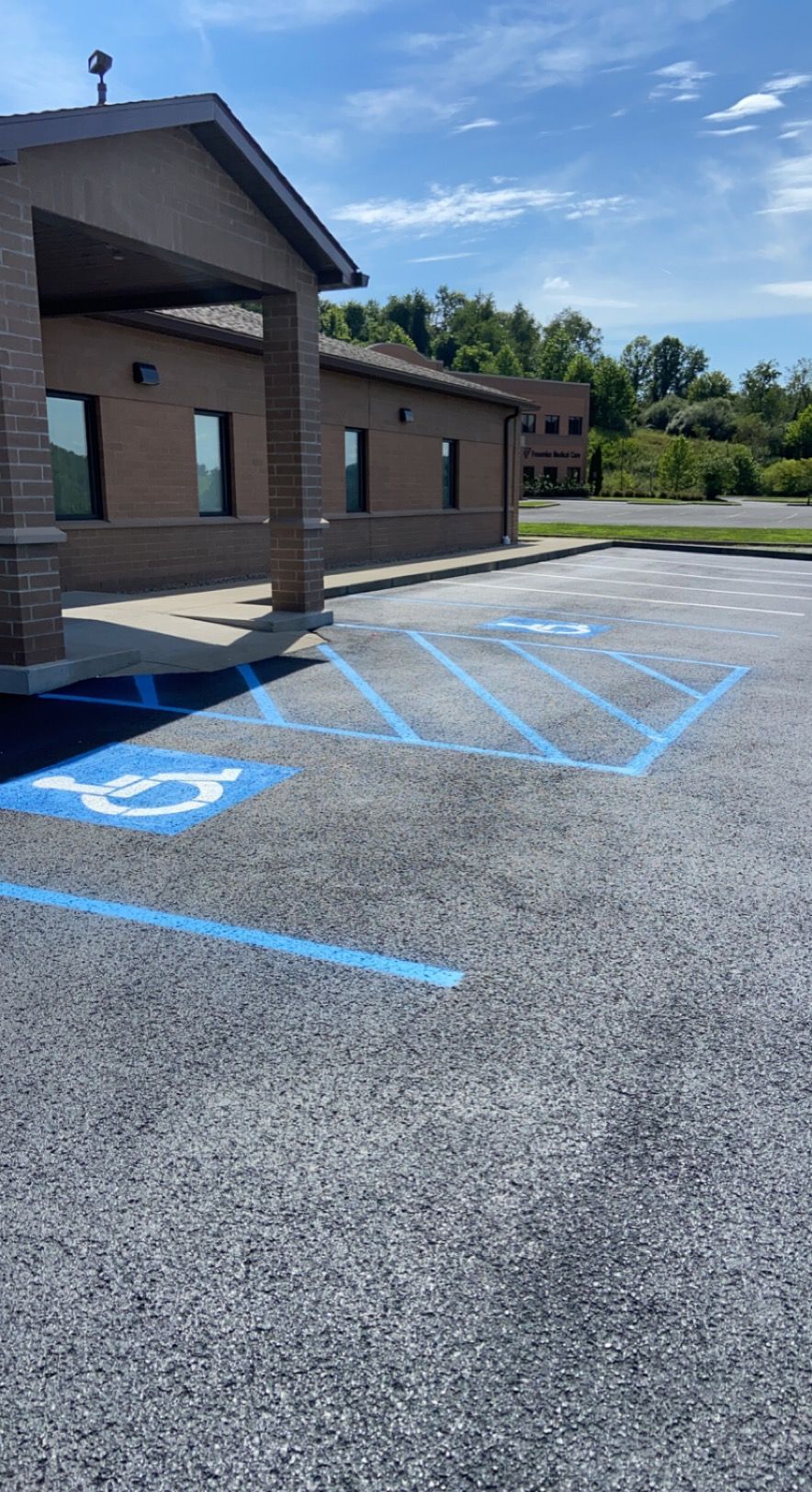Exterior view of a building with a blue painted handicap parking spot in an asphalt parking lot.