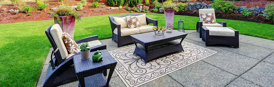 Patio furniture set on stone patio with a rug and grass in the background.