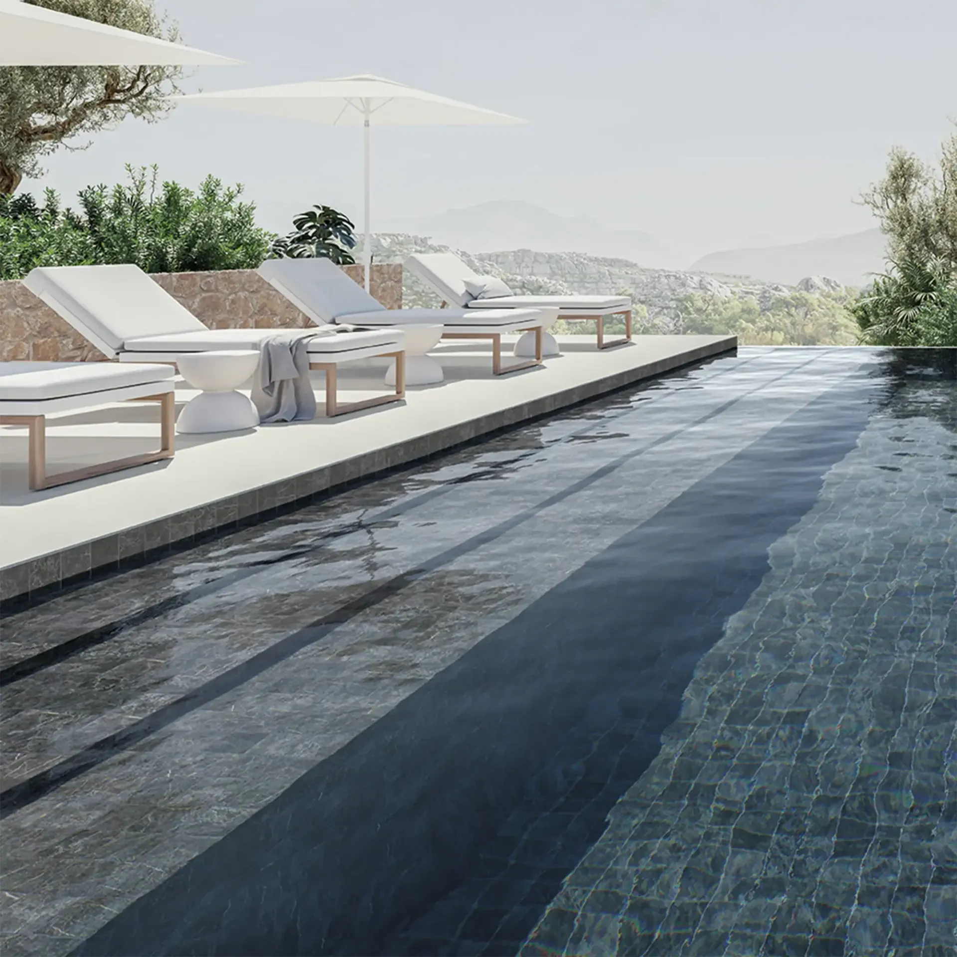 Poolside scene with lounge chairs, umbrellas, and a view of mountains.