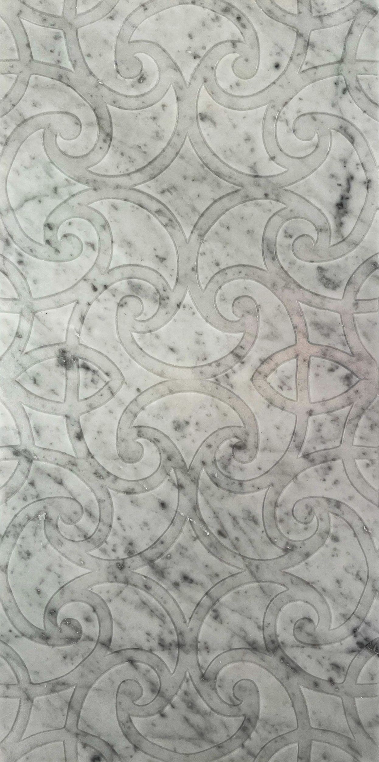 White marble surface with swirling etched design, mottled with gray speckles.