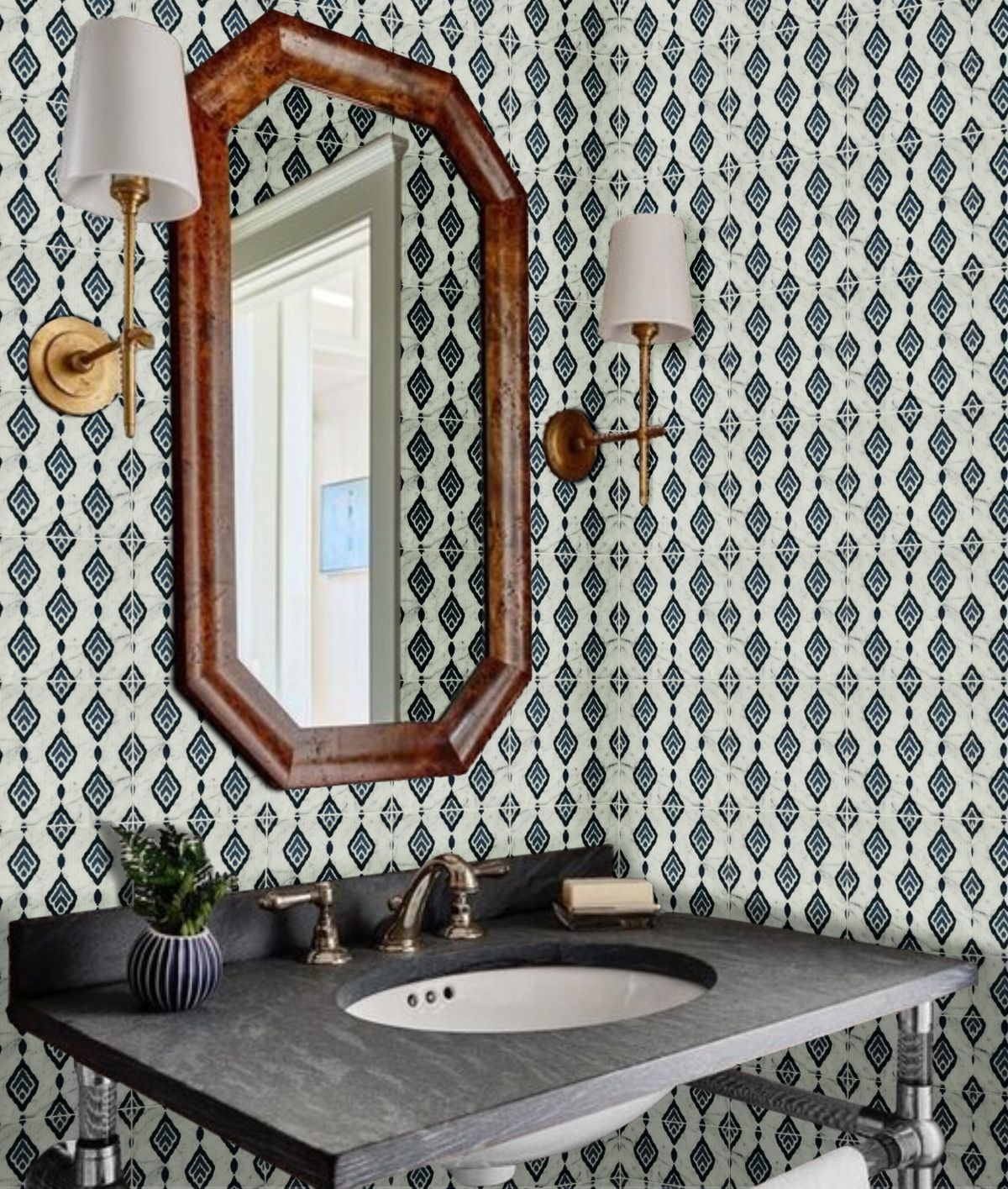 Bathroom with patterned wallpaper, dark vanity, ornate mirror, and sconces.