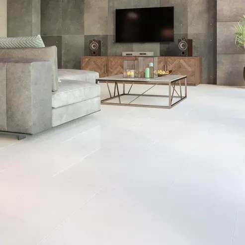 Living room with white floor, gray couch, TV, wooden cabinet, and coffee table.