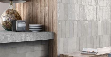 A kitchen with light gray vertical tile wall and wooden accents, featuring a countertop with decor.