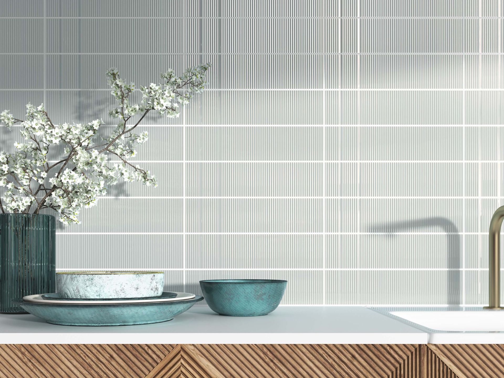 A kitchen counter with a vase of white flowers, plates, and a bowl against a tiled wall.