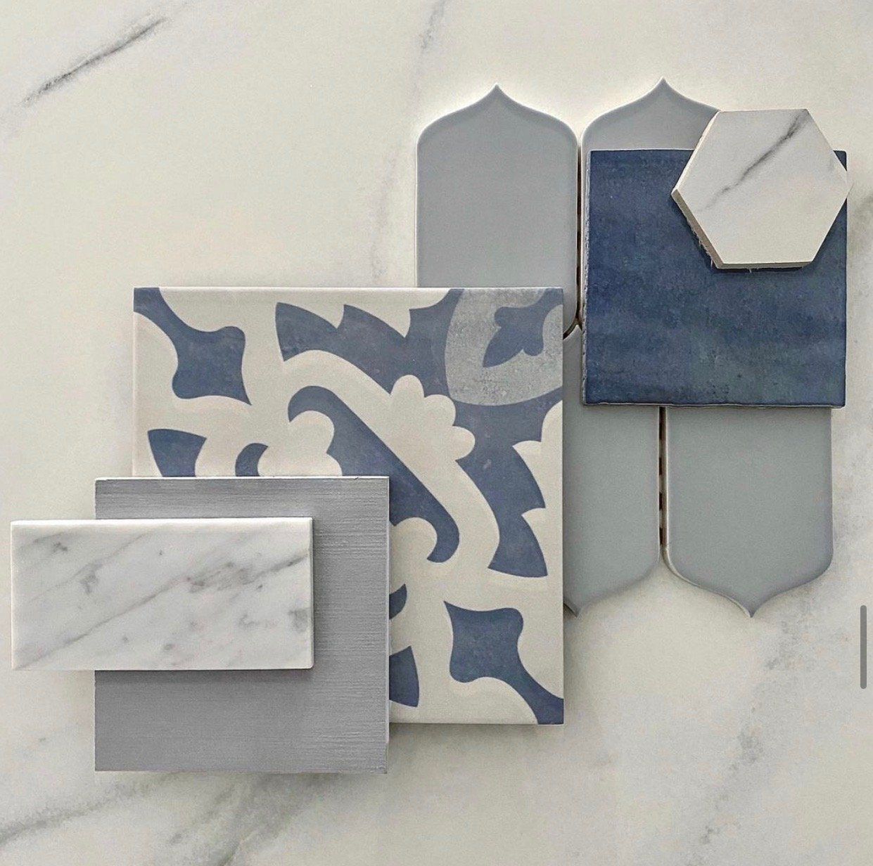 A tile swatch featuring blue and gray tiles of various shapes and patterns on a marble surface.