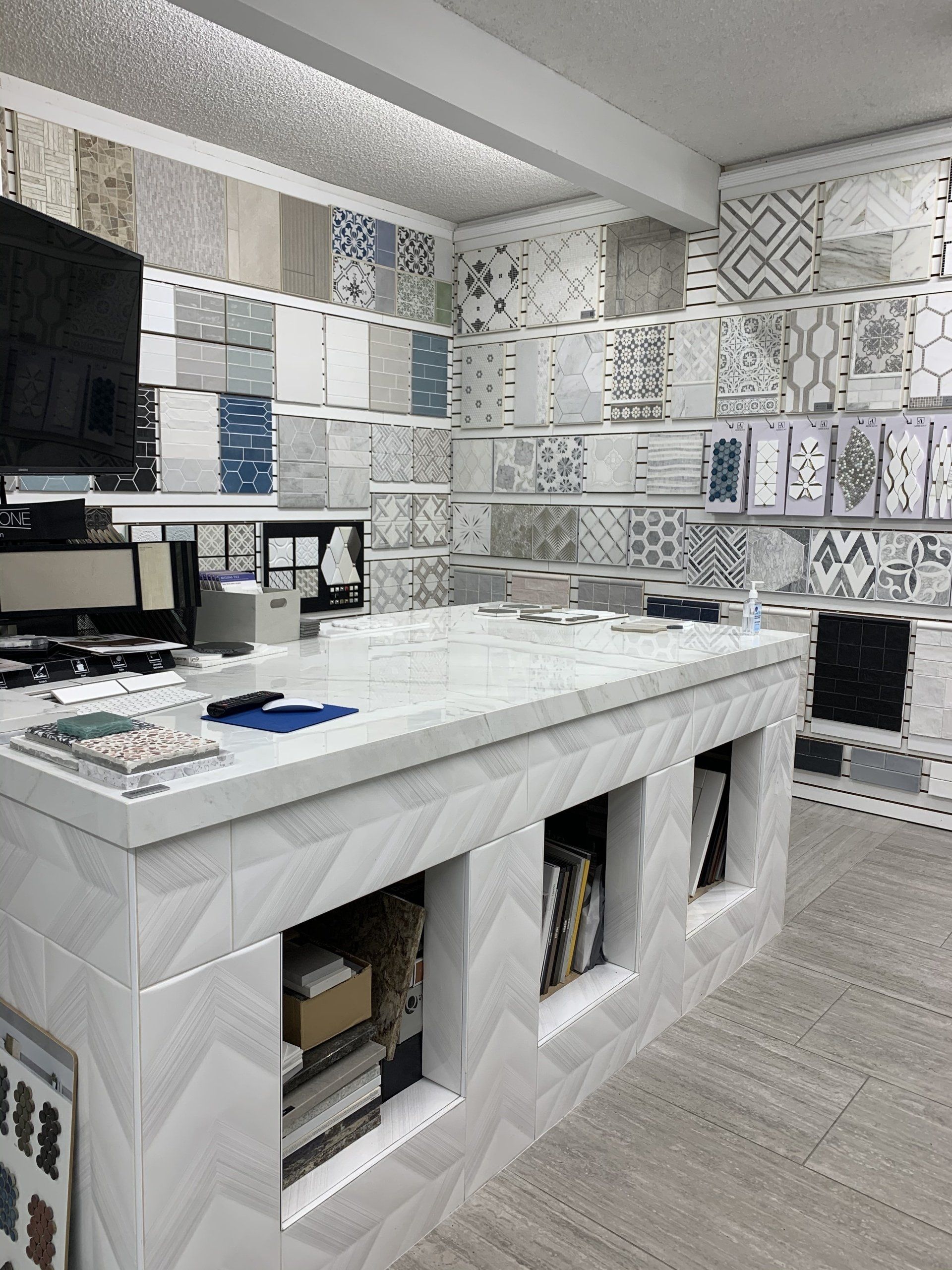 A tile store interior with various tile samples displayed on the walls. Counter in front.