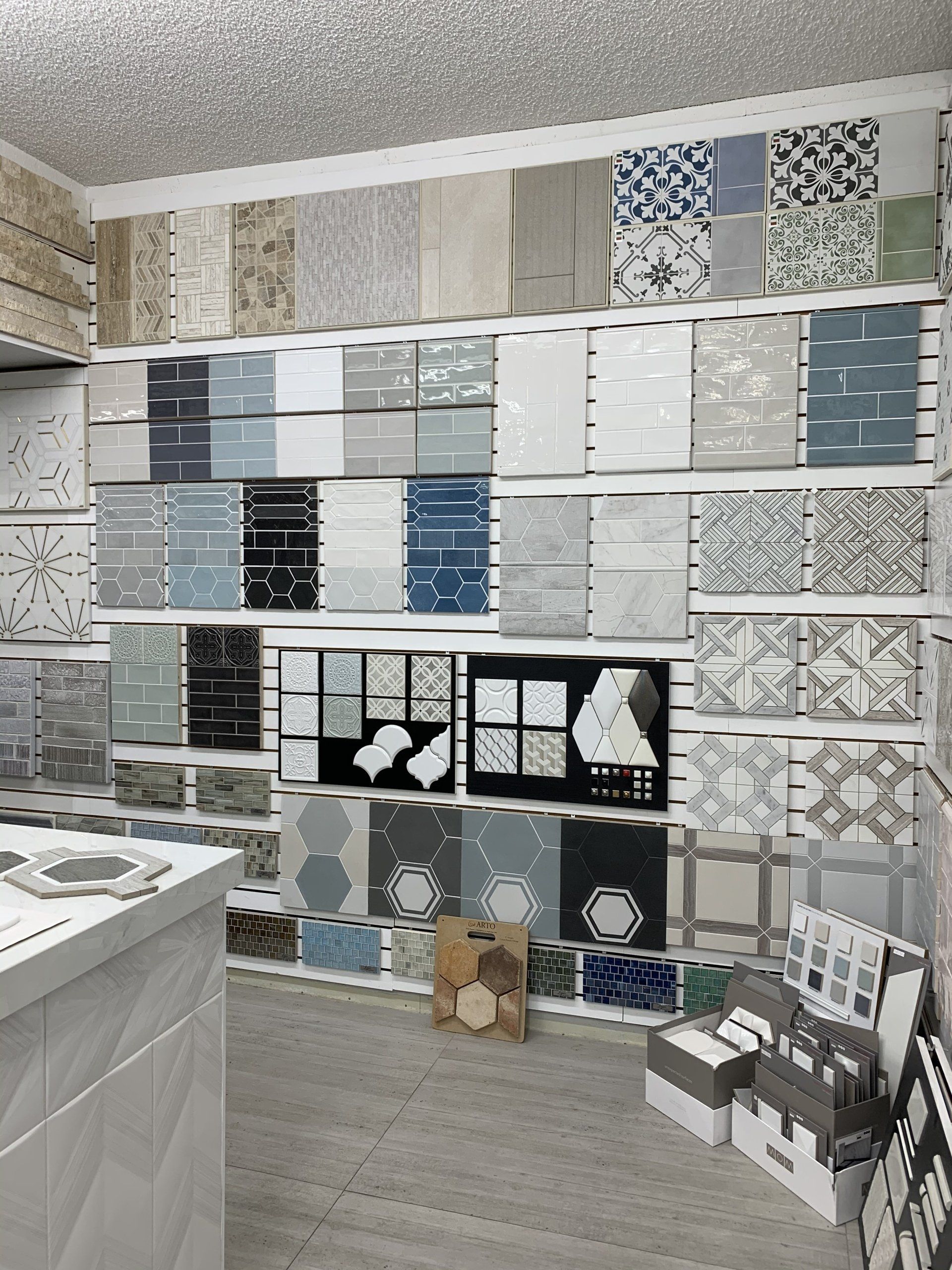 Tile samples displayed on walls and counters in a showroom, showcasing various colors and patterns.