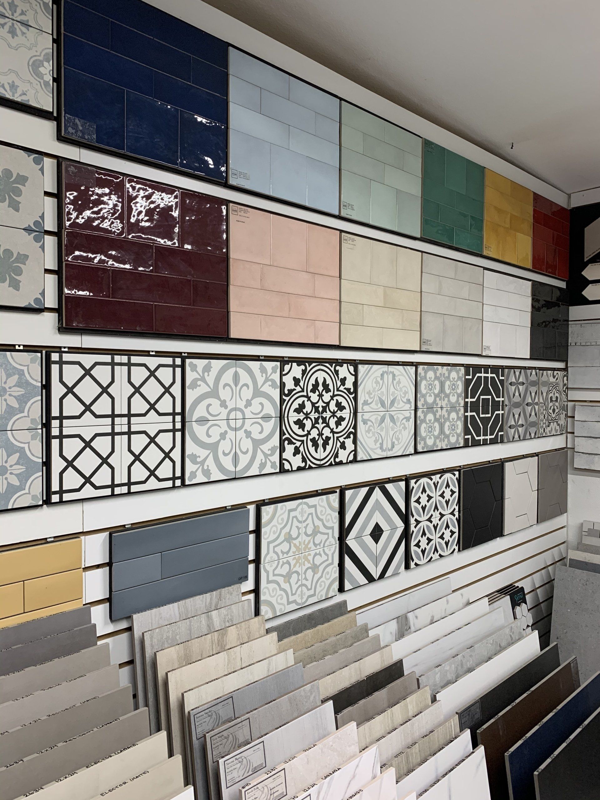 Tile samples in various colors and patterns displayed on a wall at a showroom.