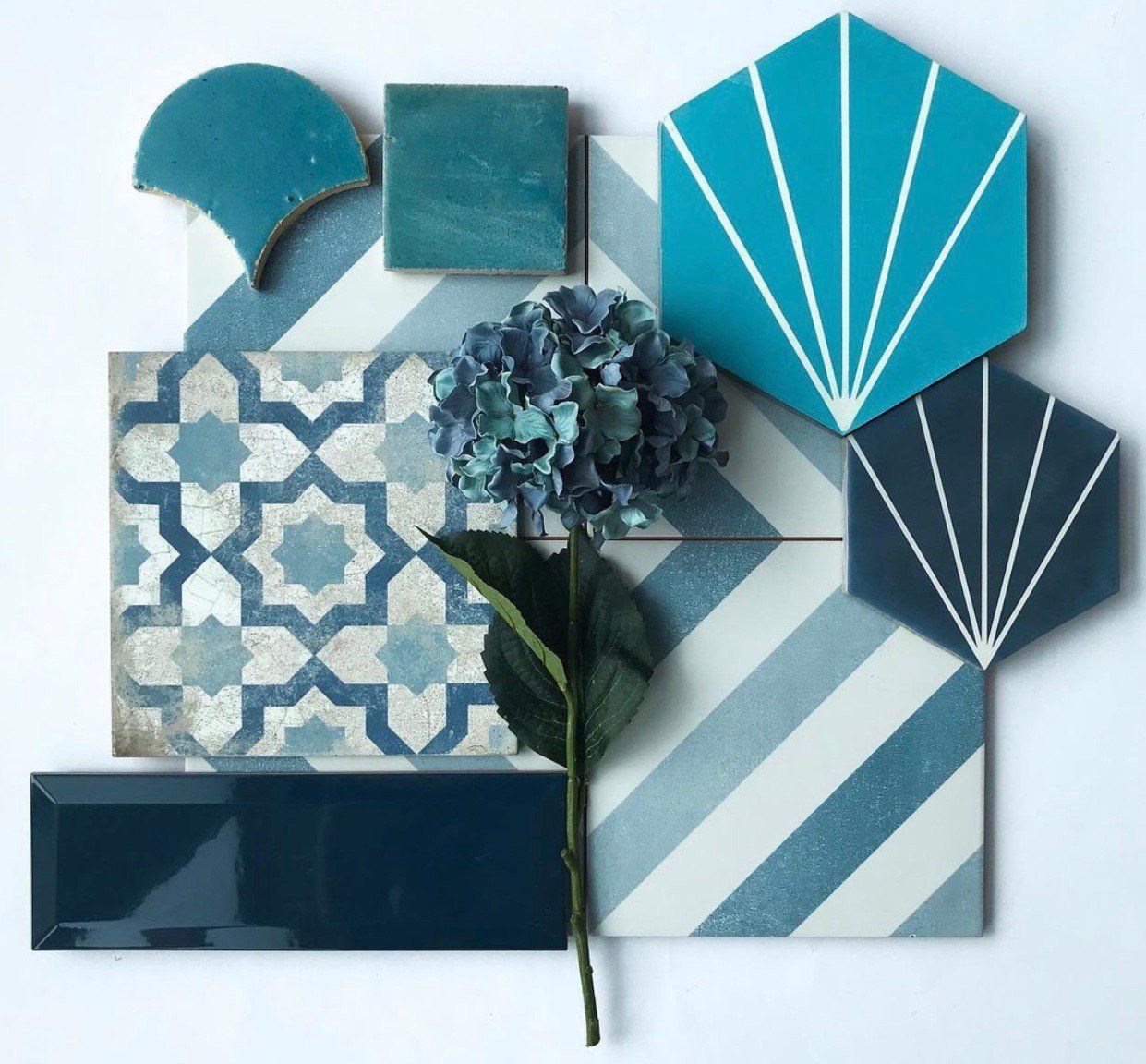 Blue tile samples arranged with a hydrangea flower. Includes patterned, geometric, and solid tiles in various shades of blue.