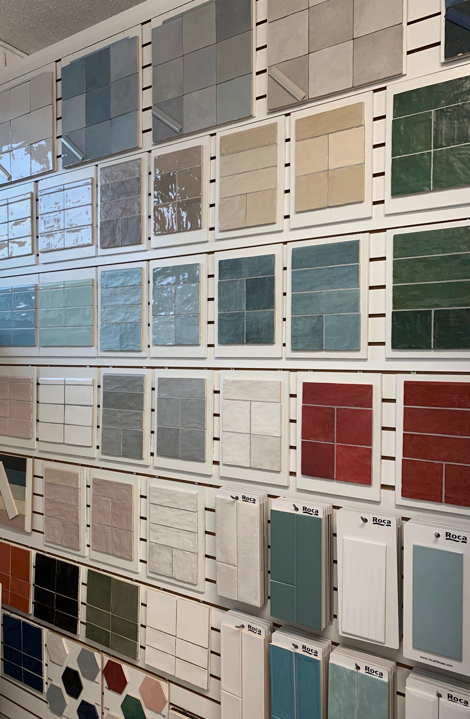 Tile samples displayed on a store wall; various colors and textures, including blues, greens, reds, and neutrals.