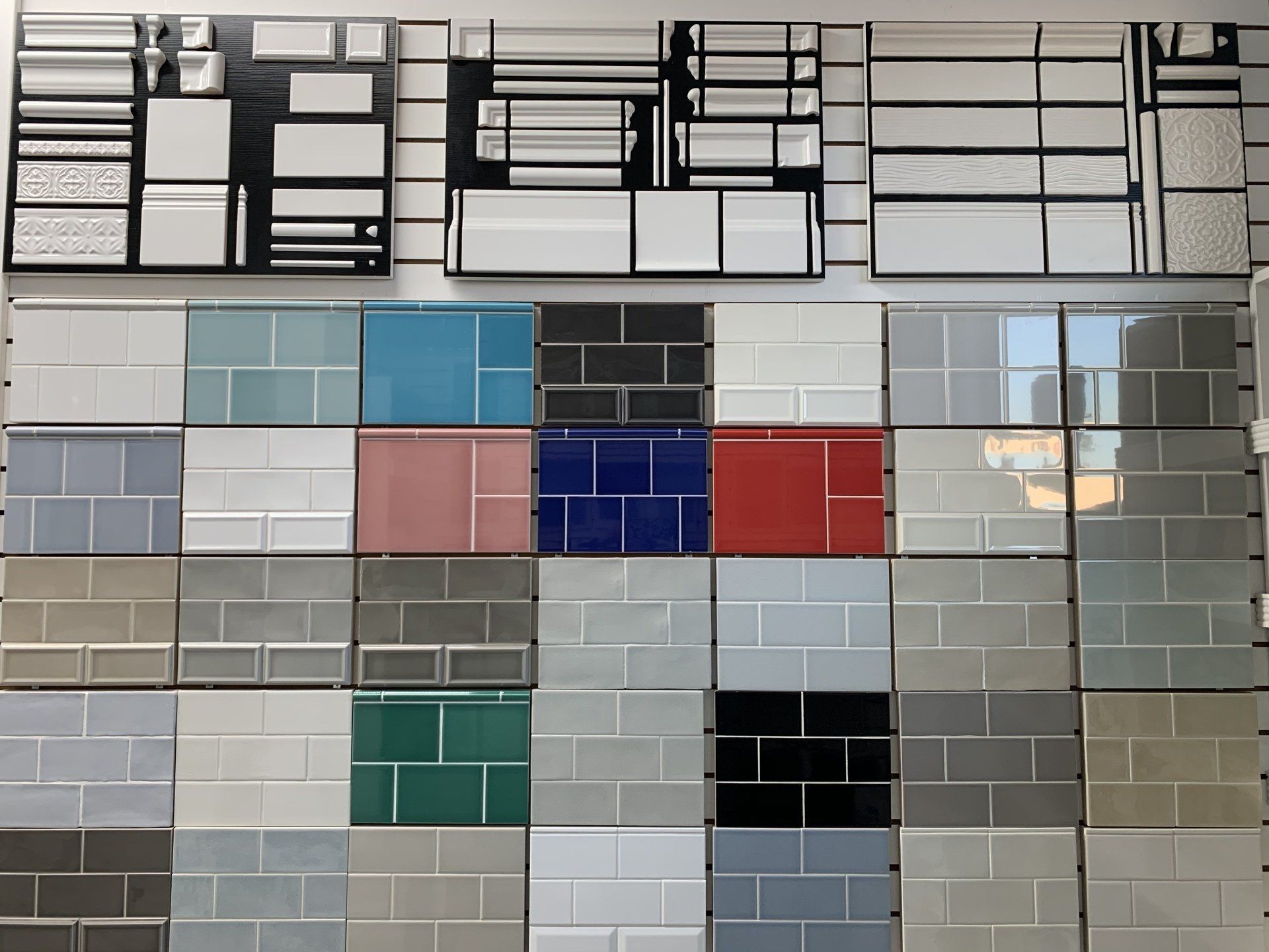 A display of various colorful ceramic tile samples arranged on a wall, for design selection.