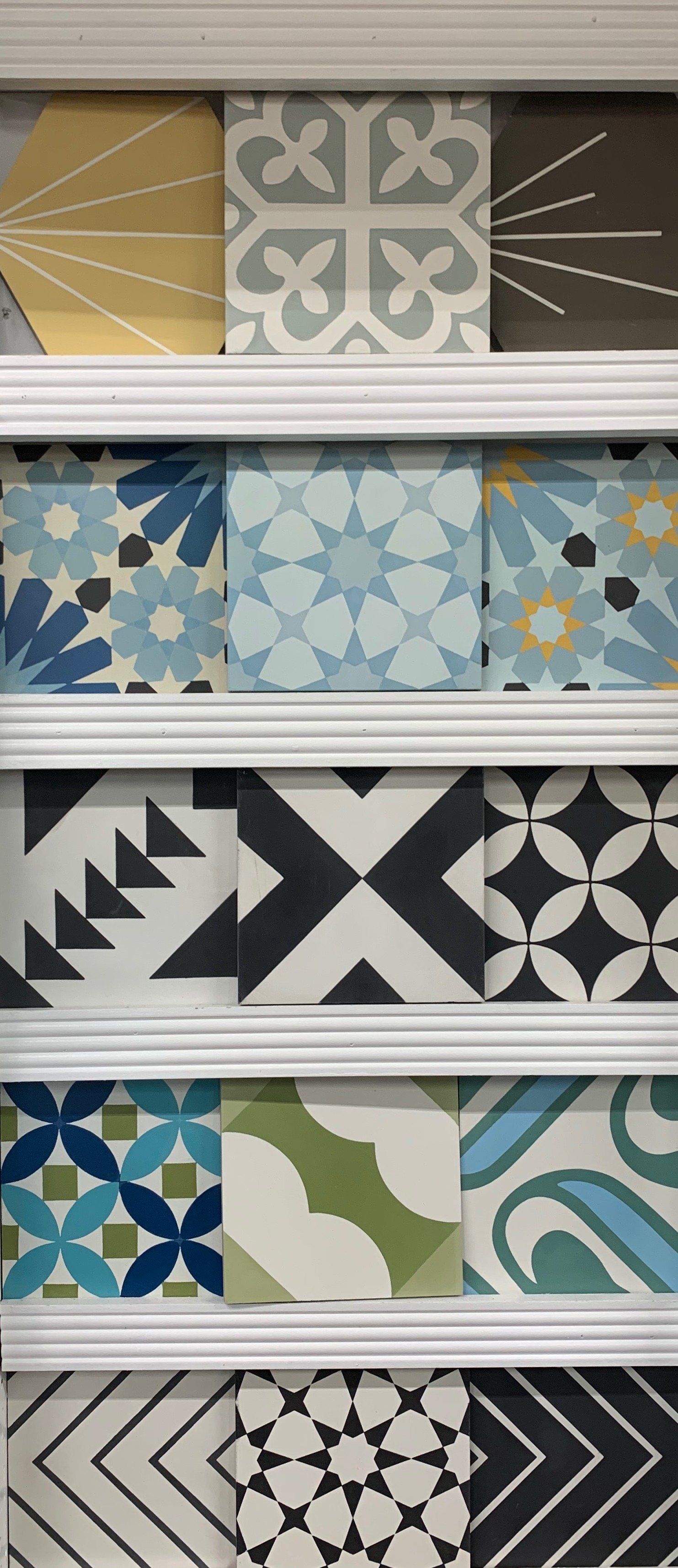 Display of decorative tiles in various patterns and colors, arranged in rows.