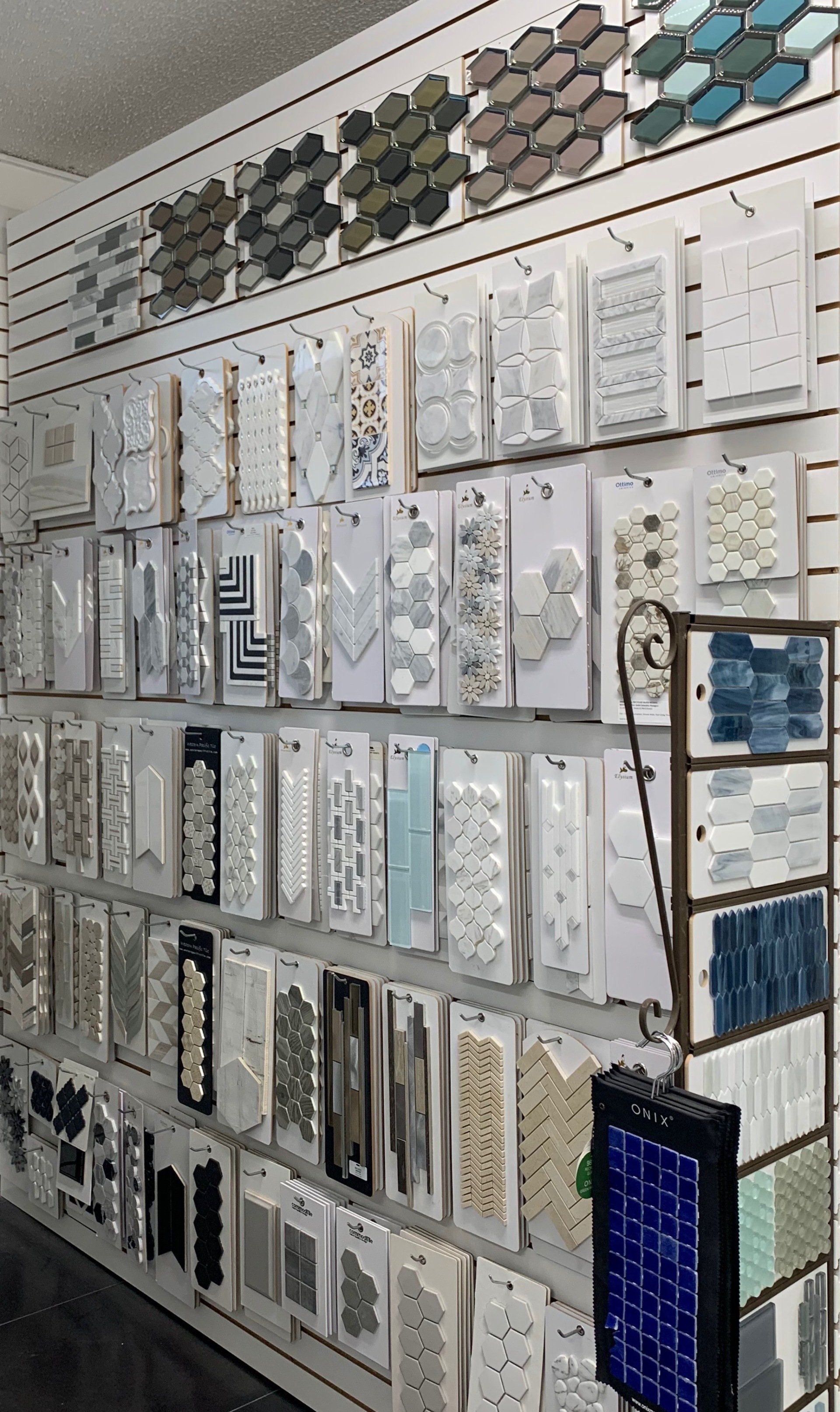 Tile display wall, various patterns and colors. Retail setting, organized samples.