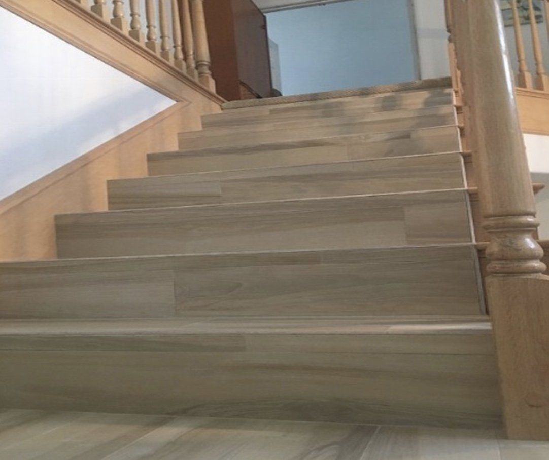 Wooden staircase with wood railing, steps are tiled.