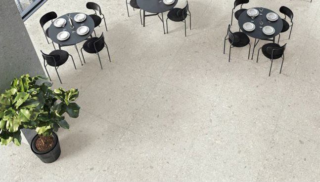 Overhead view of a room with three round tables with plates and chairs. A potted plant sits near a wall.