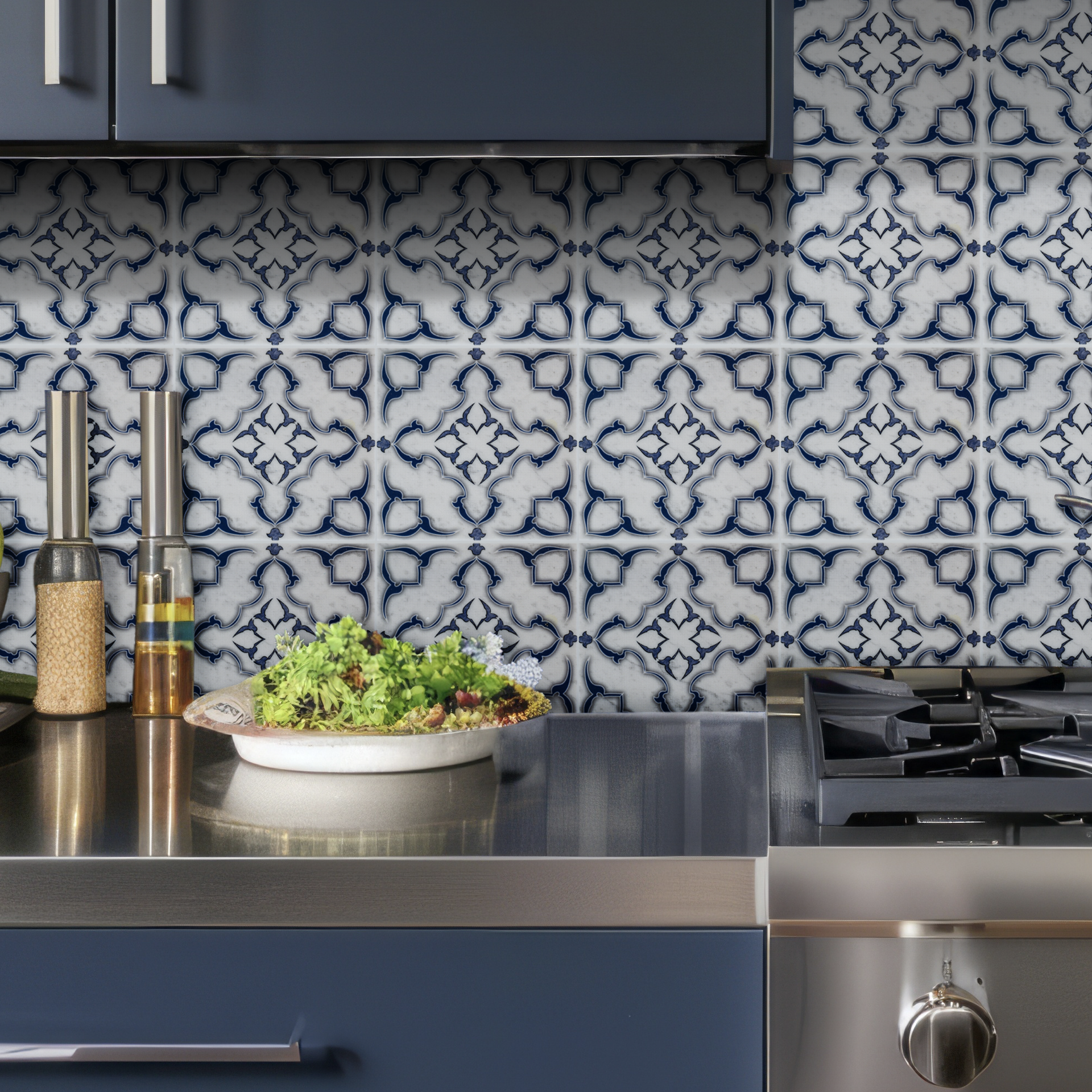 Blue and white patterned tile backsplash above a stainless steel countertop and blue cabinetry.