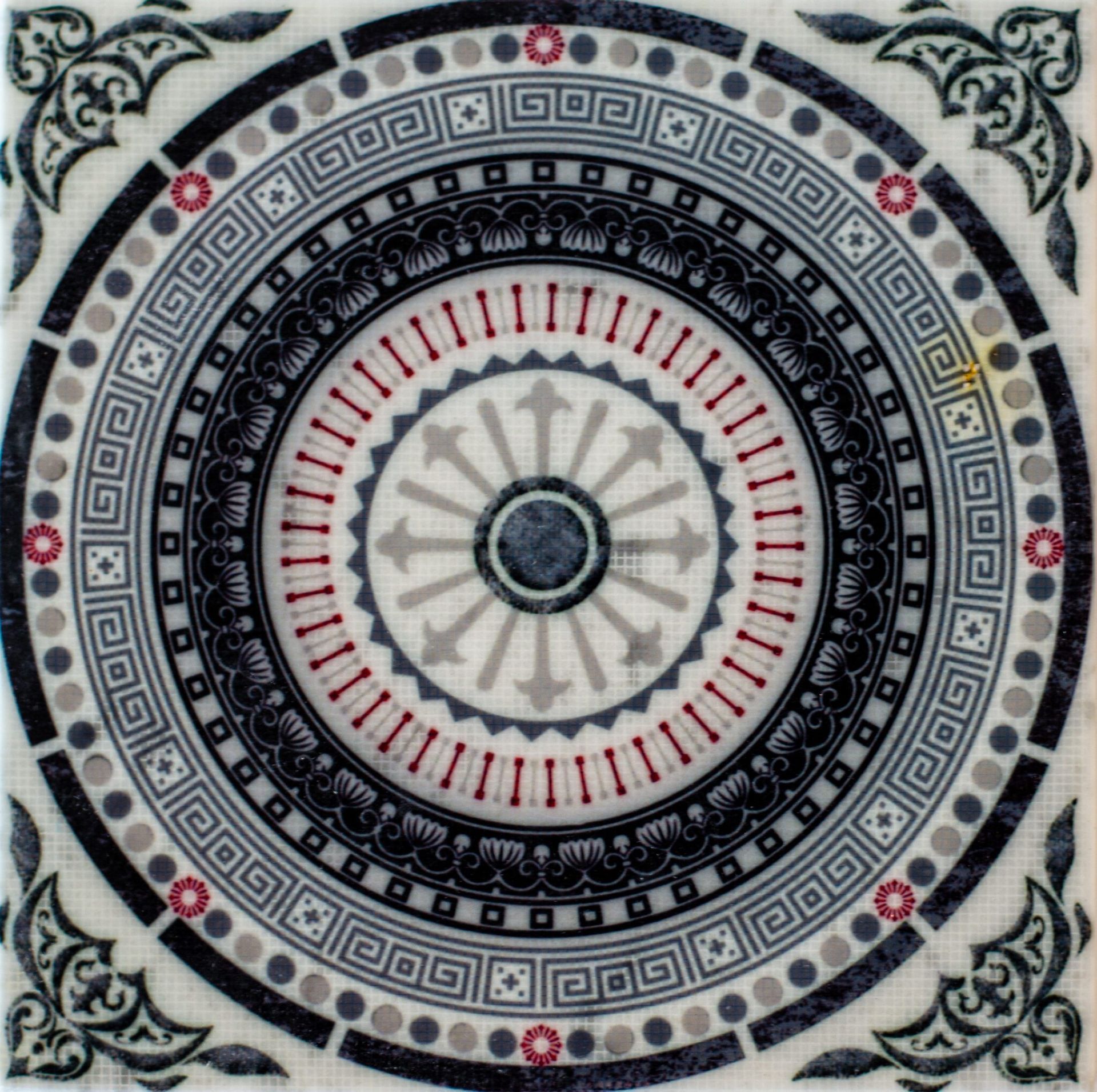 Decorative tile with a circular design in blues, grays, and red, featuring repeating patterns and a central medallion.