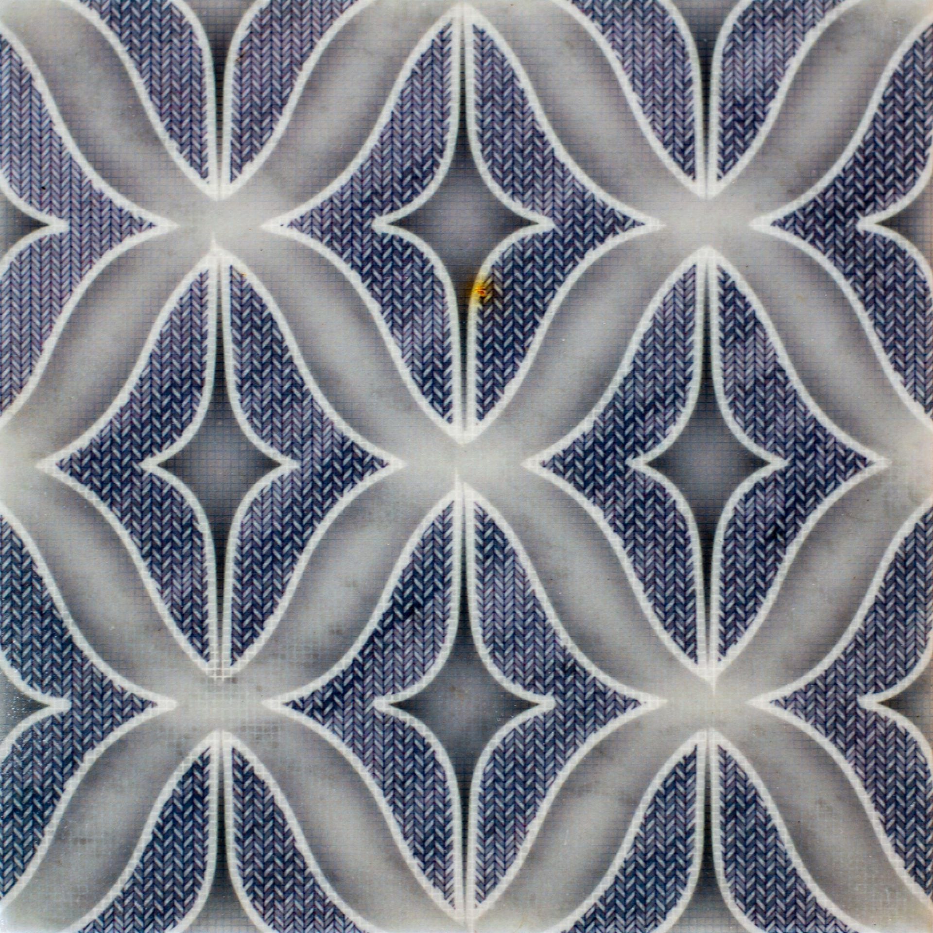 Blue and white patterned tile with stylized floral motif.