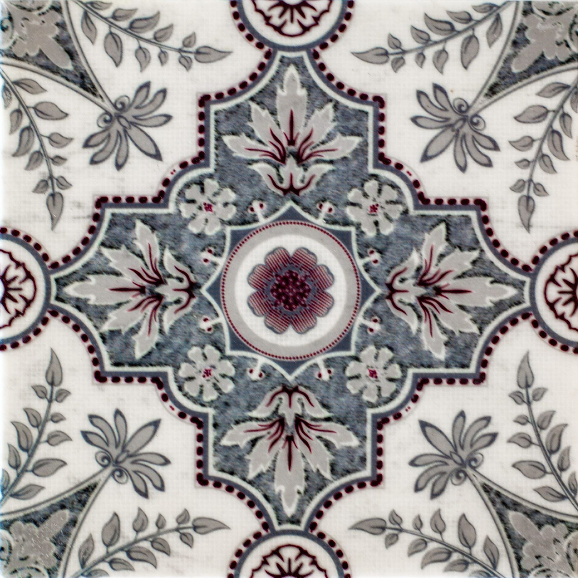 Decorative tile with gray and maroon floral pattern on white background.