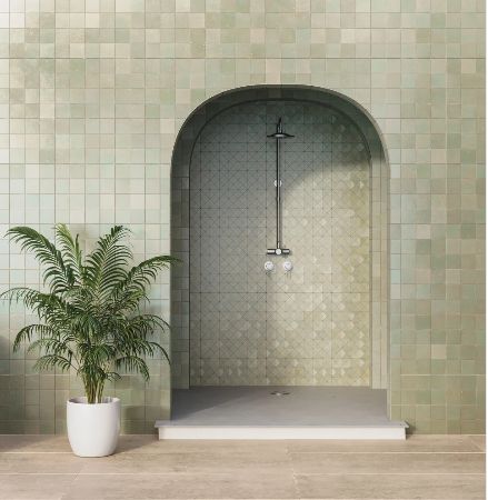 Green tiled shower with archway, showerhead, and a potted plant.