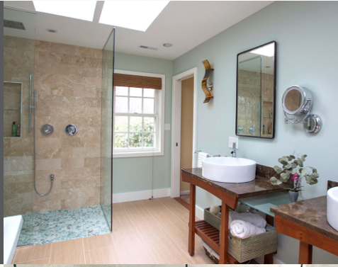 Bathroom with glass shower, light blue walls, wooden vanities, and a large mirror.