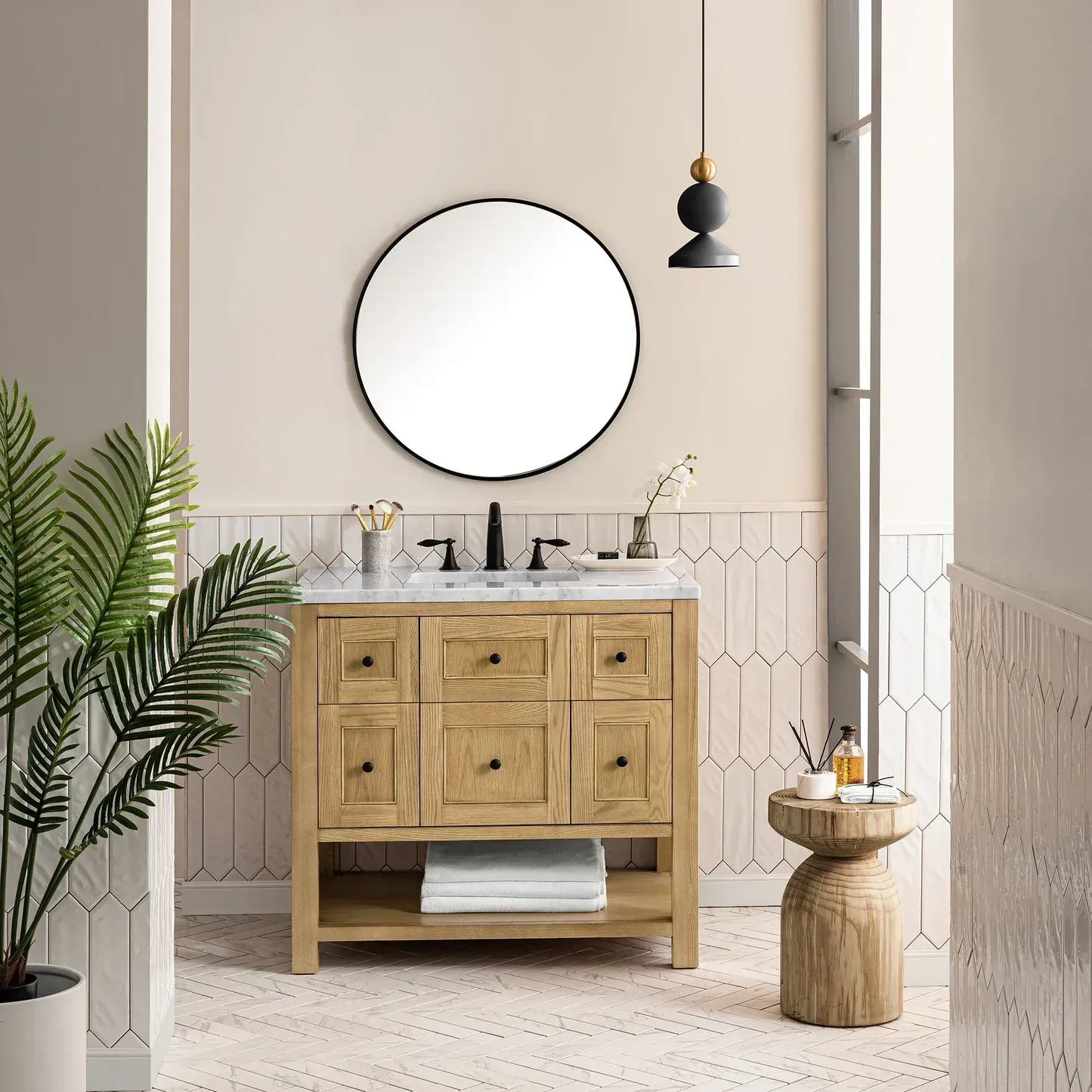 Bathroom with wooden vanity, round mirror, patterned wall, potted plant, and small side table.