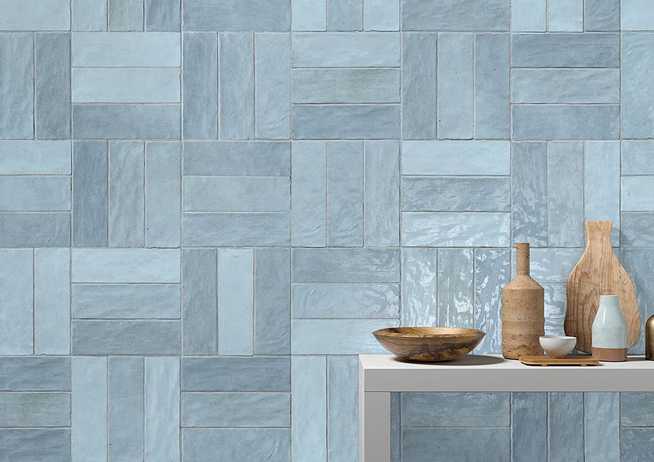 Blue-tiled wall backdrop with a white shelf holding decorative bottles and a bowl.