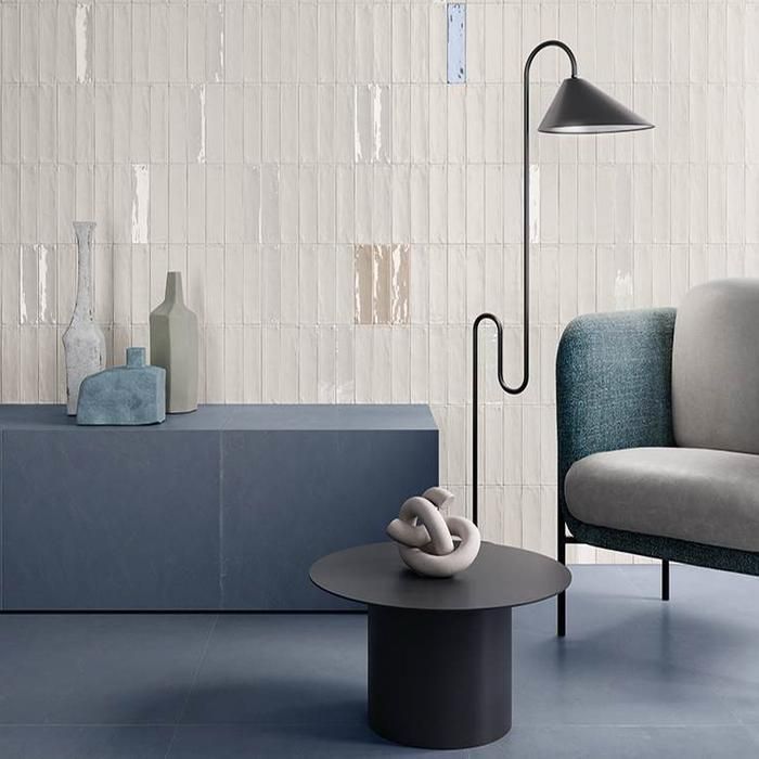Modern living room with white textured wall, black floor lamp, blue sofa, and black side table.