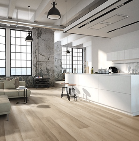 Modern loft-style kitchen with white cabinets, light wood floor, and exposed concrete wall.