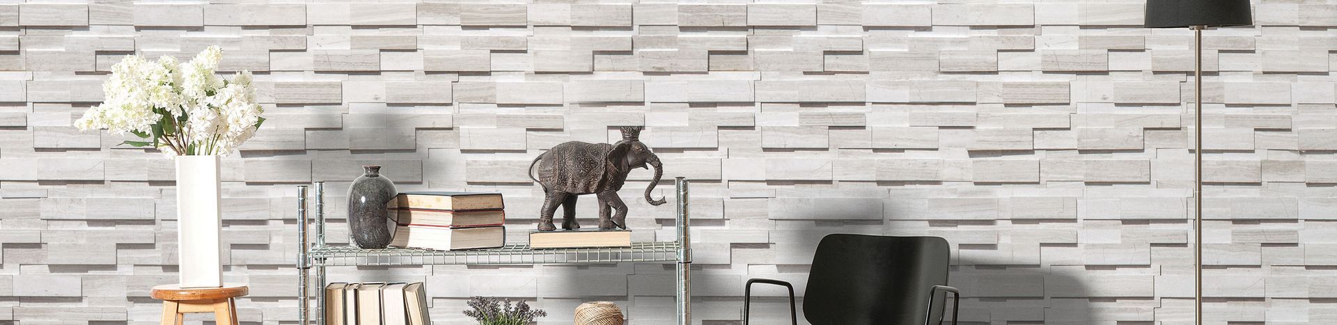 Living room with white brick wall, shelf with elephant, flowers and black chair.