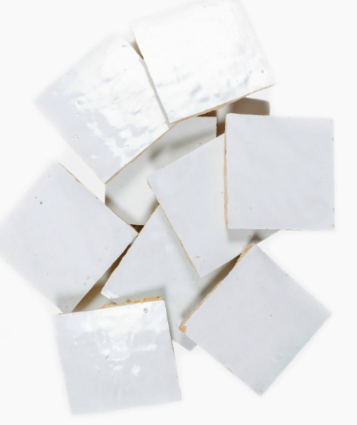 Scattered pile of white square ceramic tiles.