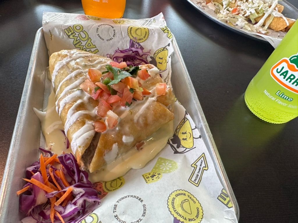 Two drizzled crepes with salsa and slaw on a tray beside a green Jarritos bottle