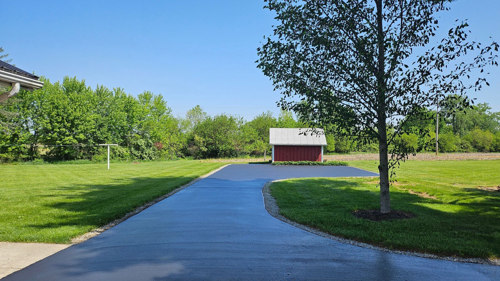 A driveway with a red barn in the background