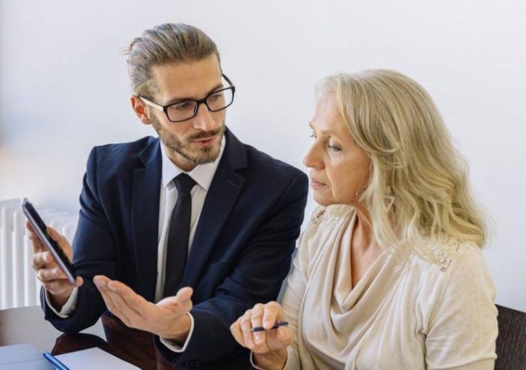 Man in suit showing tablet to woman, likely discussing finances or a plan.