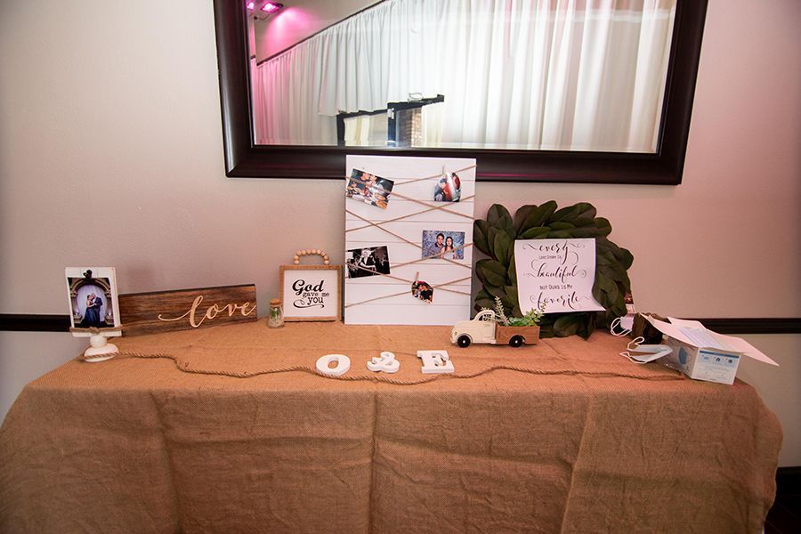 Wedding decor on a burlap-covered table with photos, signage, and a wreath. 