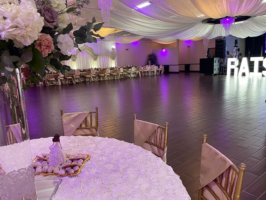 Elegant event hall with round tables, floral centerpieces, and draping ceiling decorations.