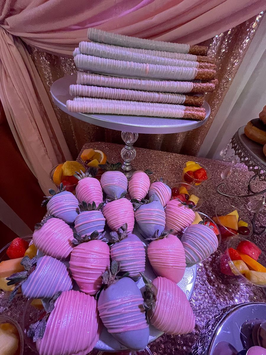 Chocolate-covered strawberries and pretzels arranged on a dessert table with pink and silver decor.