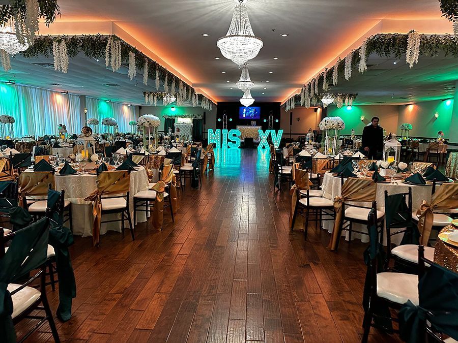 Banquet hall decorated for a Quinceañera; tables set, gold and emerald decor, 