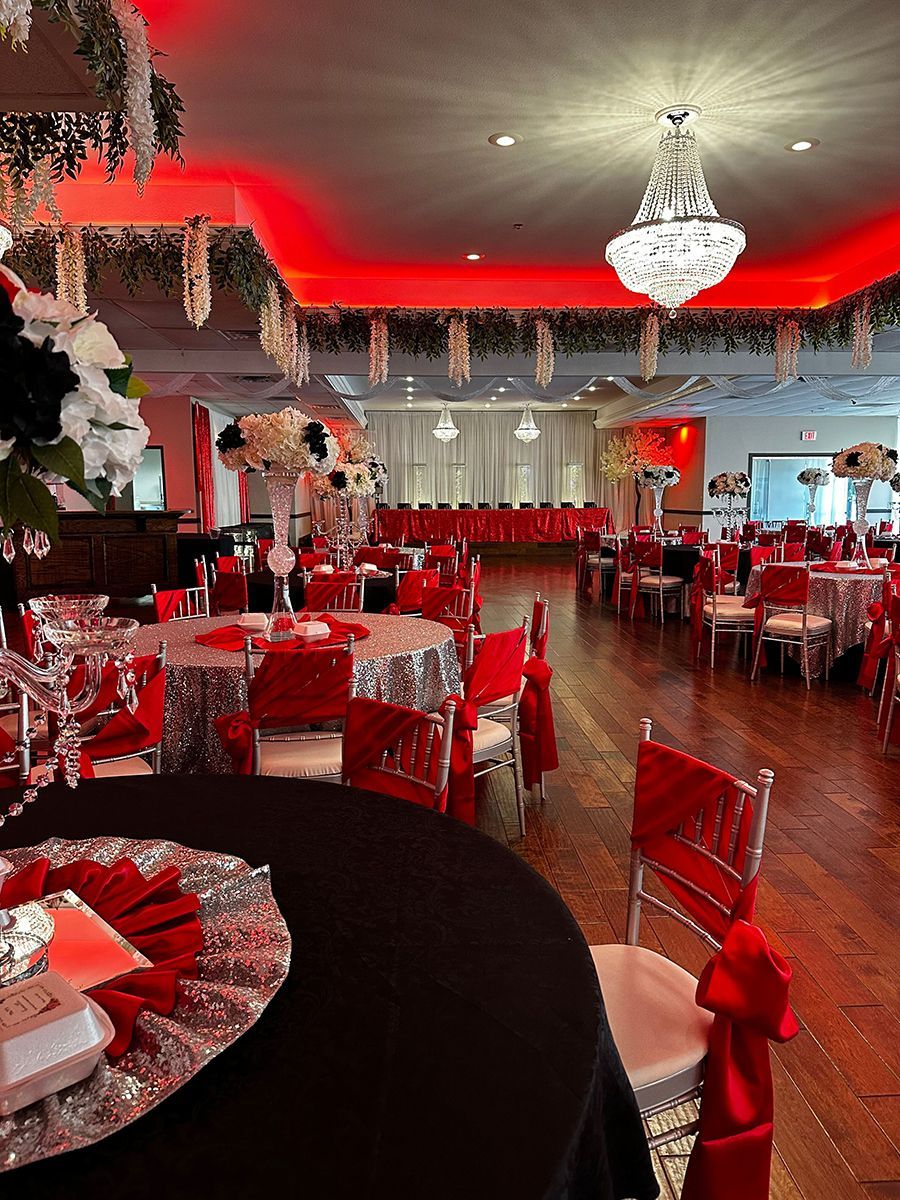 Formal event hall set for a celebration. Red and silver table settings and decorations.