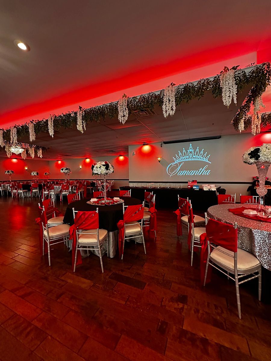 Event hall decorated with red and black accents, tables set for a party.